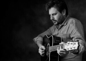 Black and white picture of Toby Lobb playing the guitar